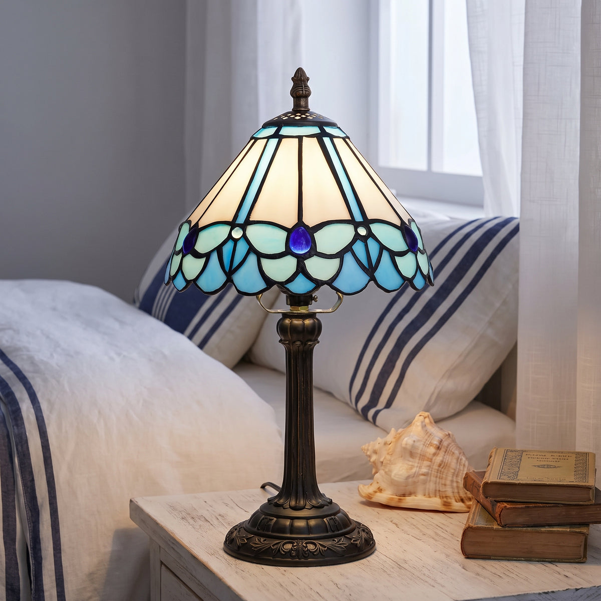 Lampe style Tiffany Lagon allumée sur une table de chevet dans une chambre bord de mer