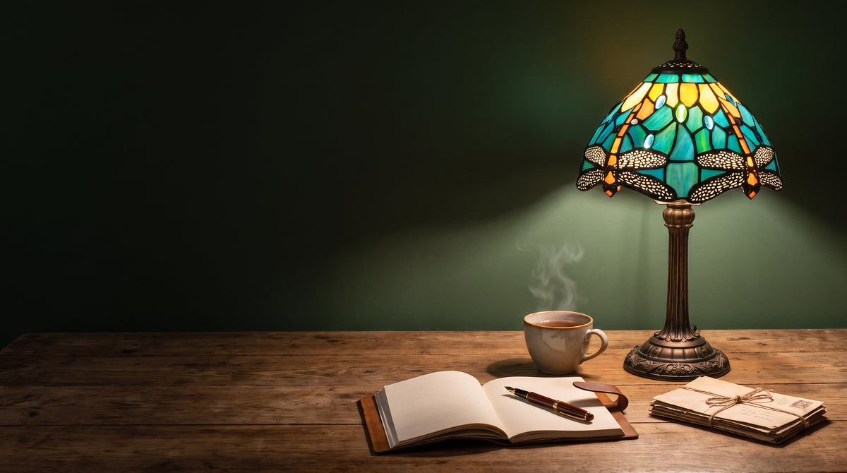 Lampe libellule turquoise allumée sur un bureau en bois avec carnet et tasse de thé