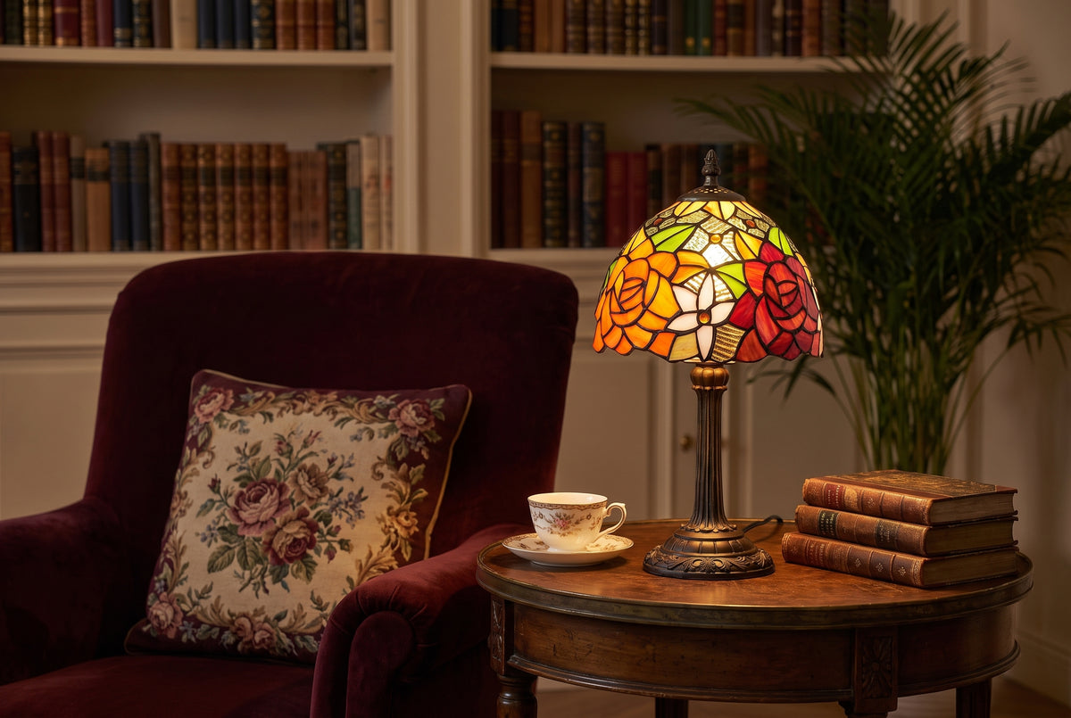 Lampe style Tiffany à roses allumée sur un guéridon à côté d'un fauteuil en velours