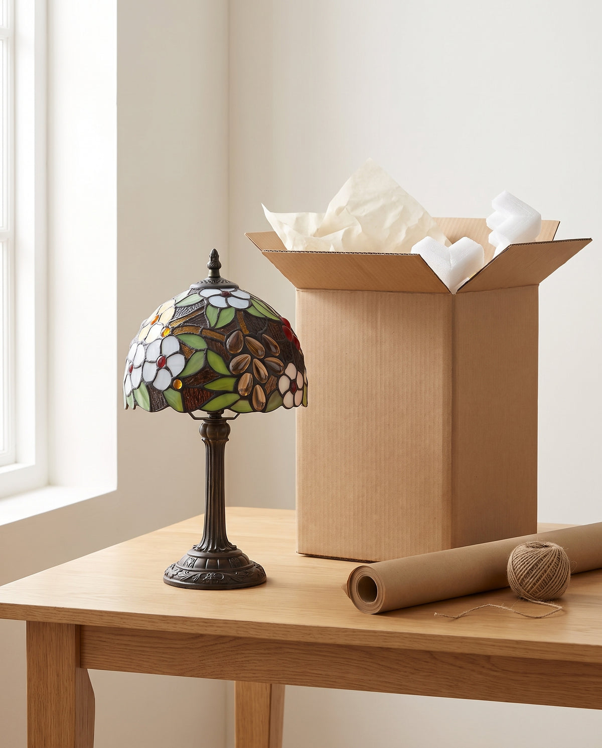 Lampe en vitrail à côté de son carton d'expédition protégé par du papier de soie et des coins en mousse